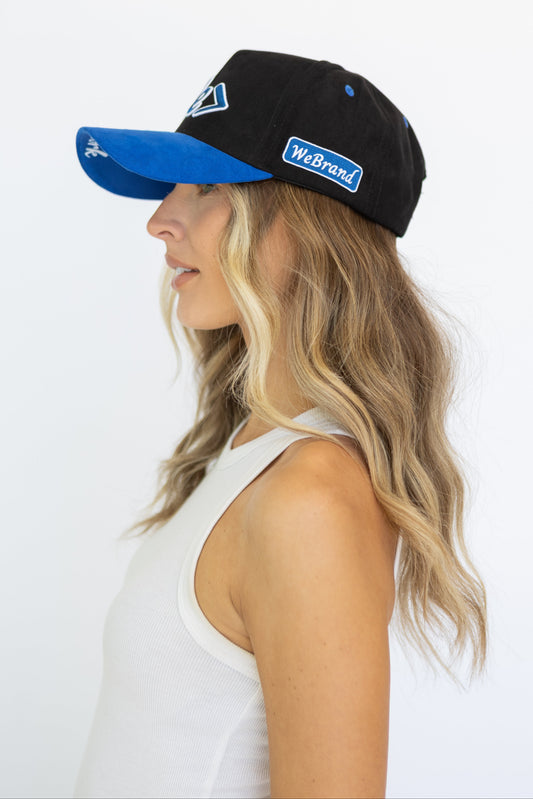 Woman wearing a black and blue cap with 'WeBrand' logo on a white background