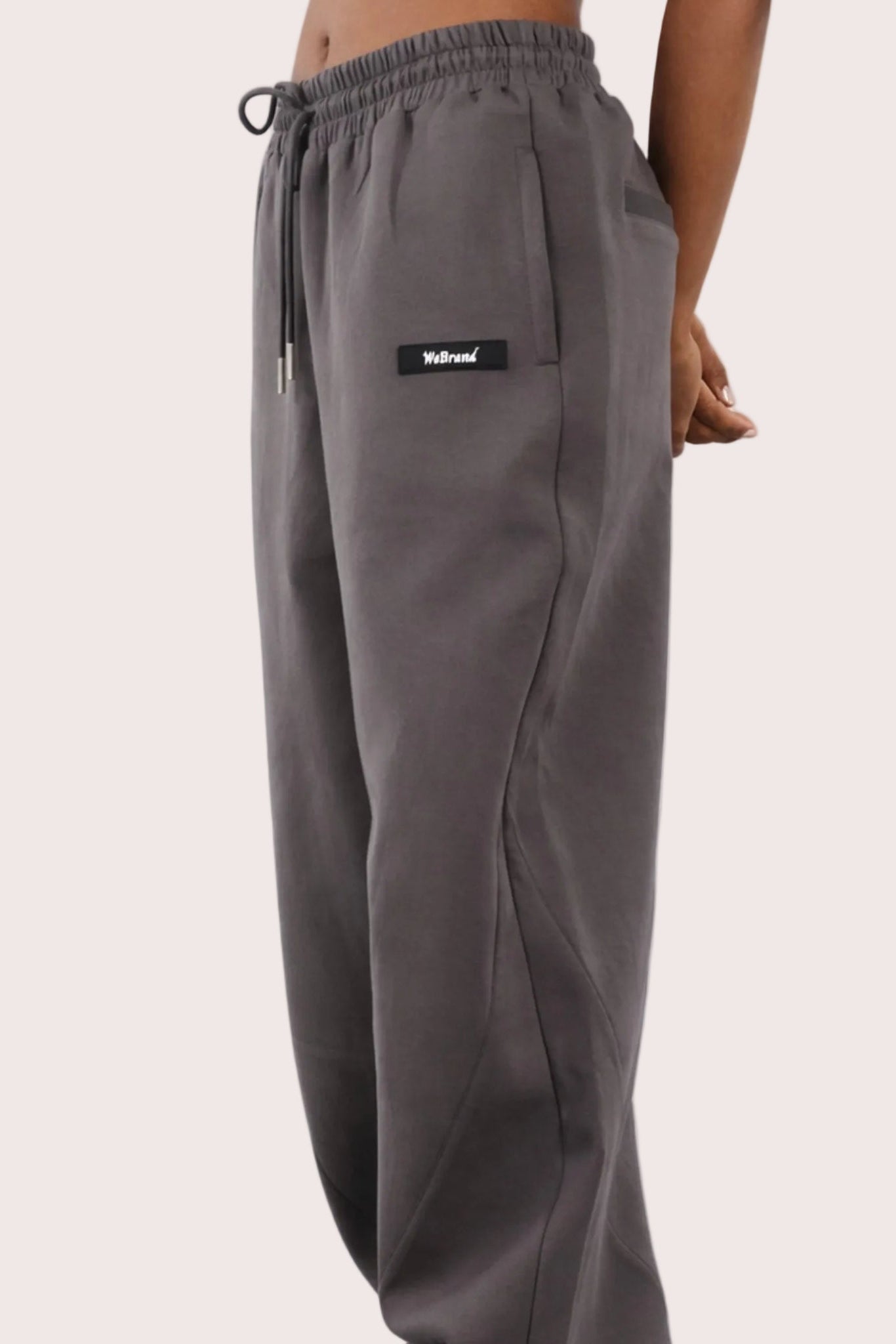 Gray sweatpants with a brand logo on a light pink background