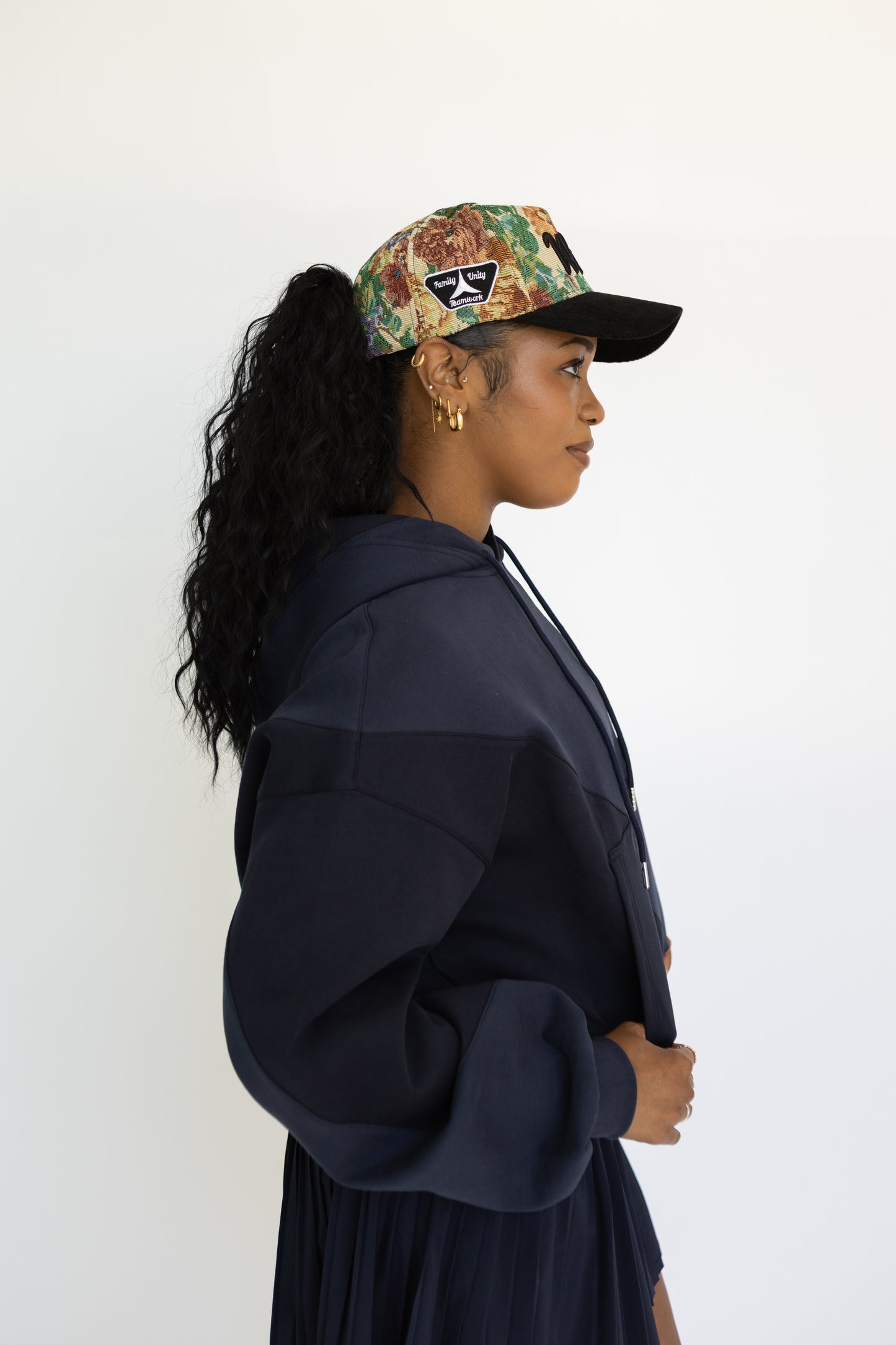 Woman wearing a patterned cap and navy jacket against a white background