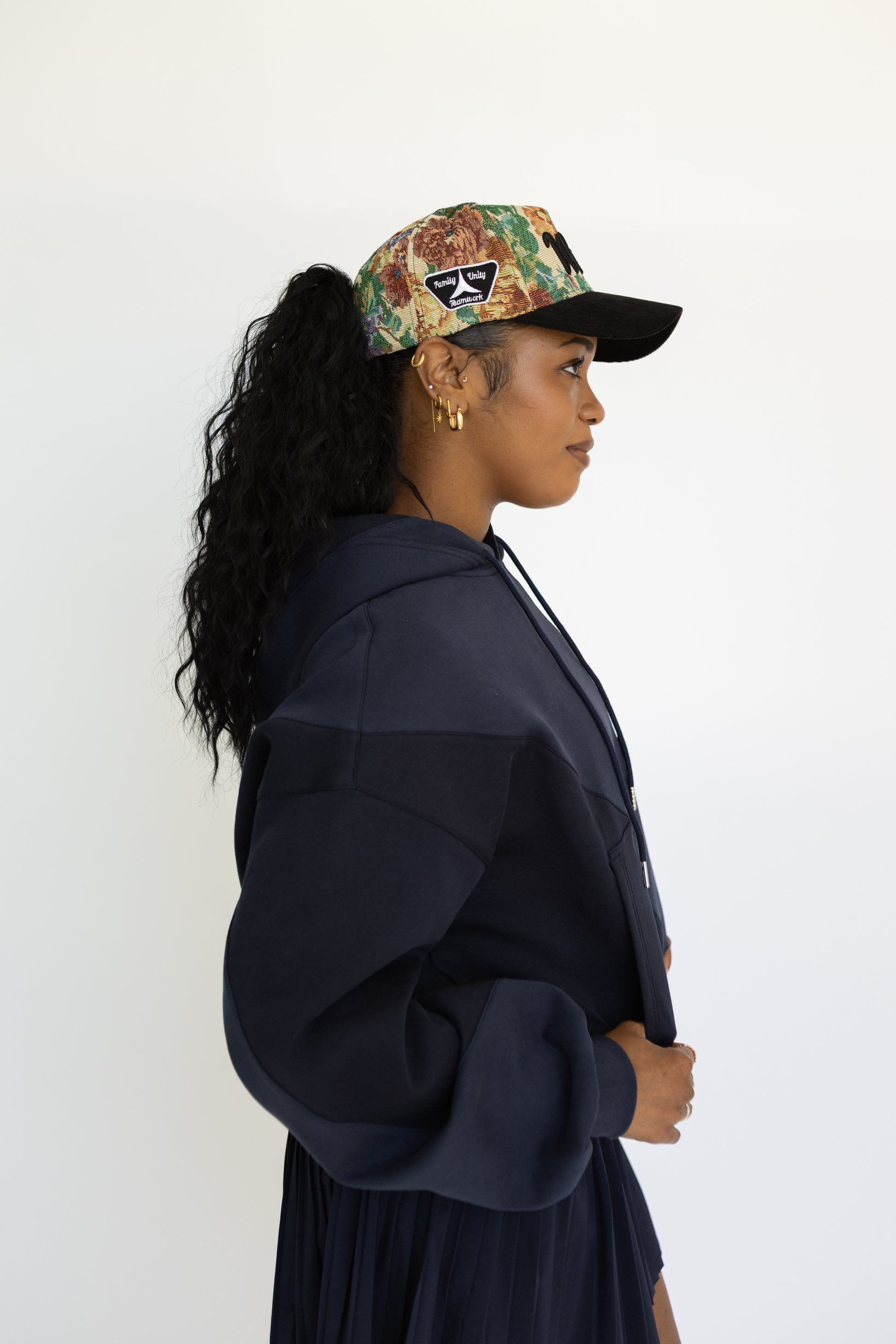 Woman wearing a patterned cap and navy jacket against a white background