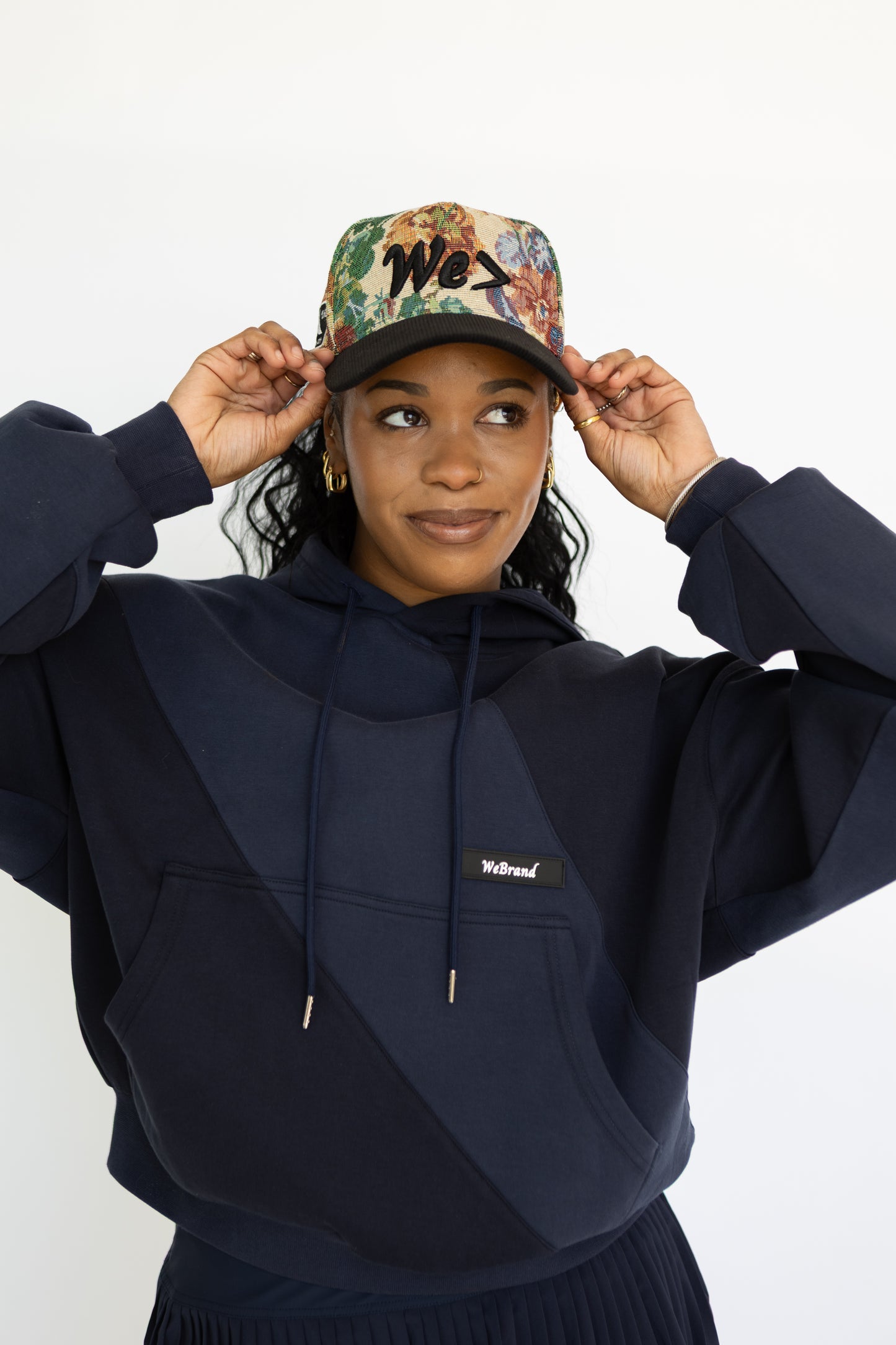 Person wearing a navy hoodie and colorful cap on a white background