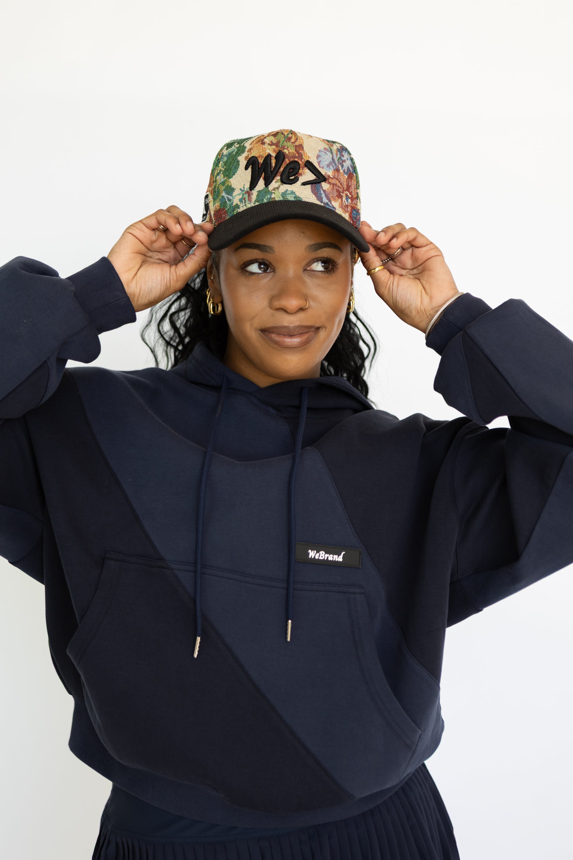 Person wearing a navy hoodie and colorful cap on a white background