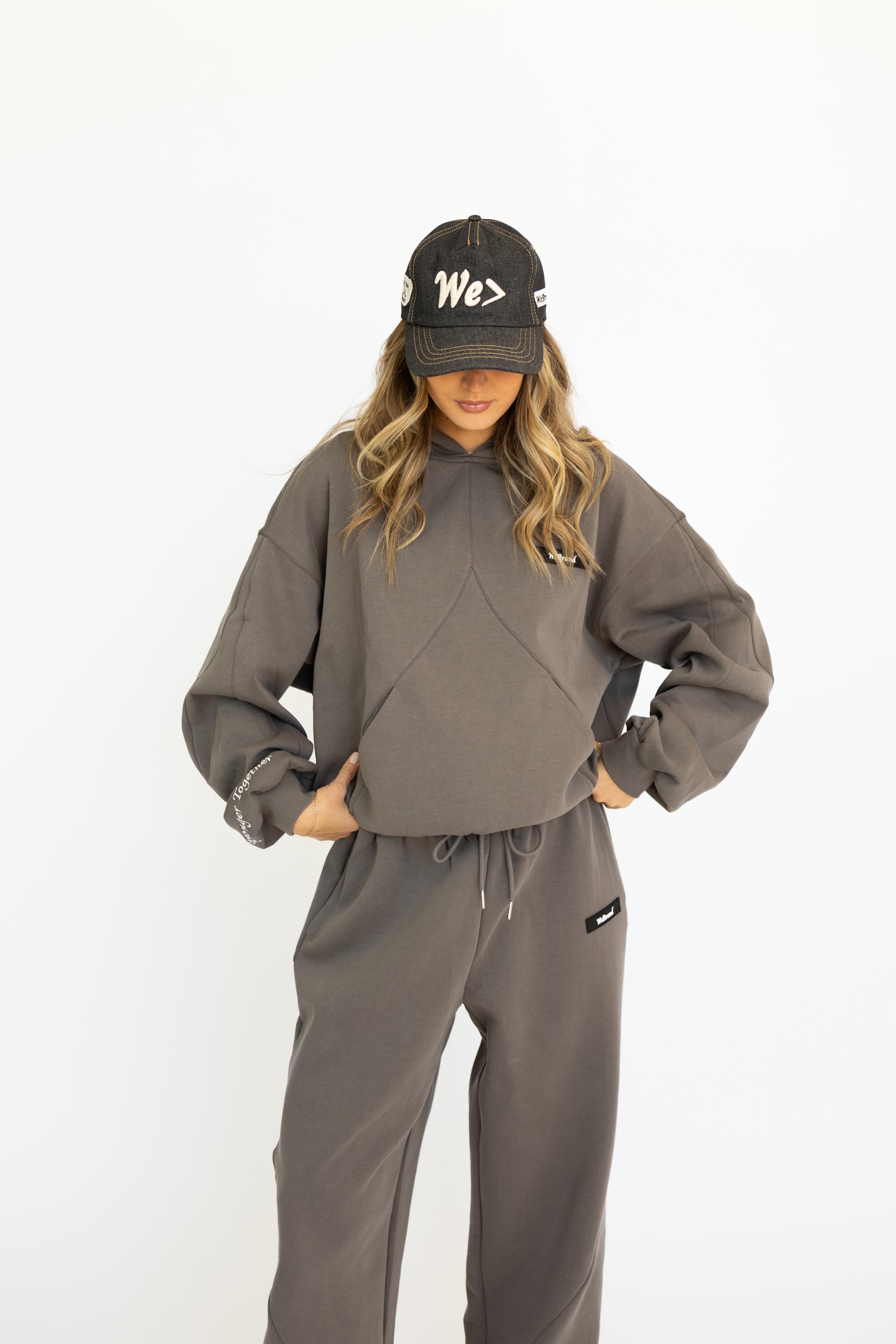 Person wearing a gray tracksuit and denim cap on a white background