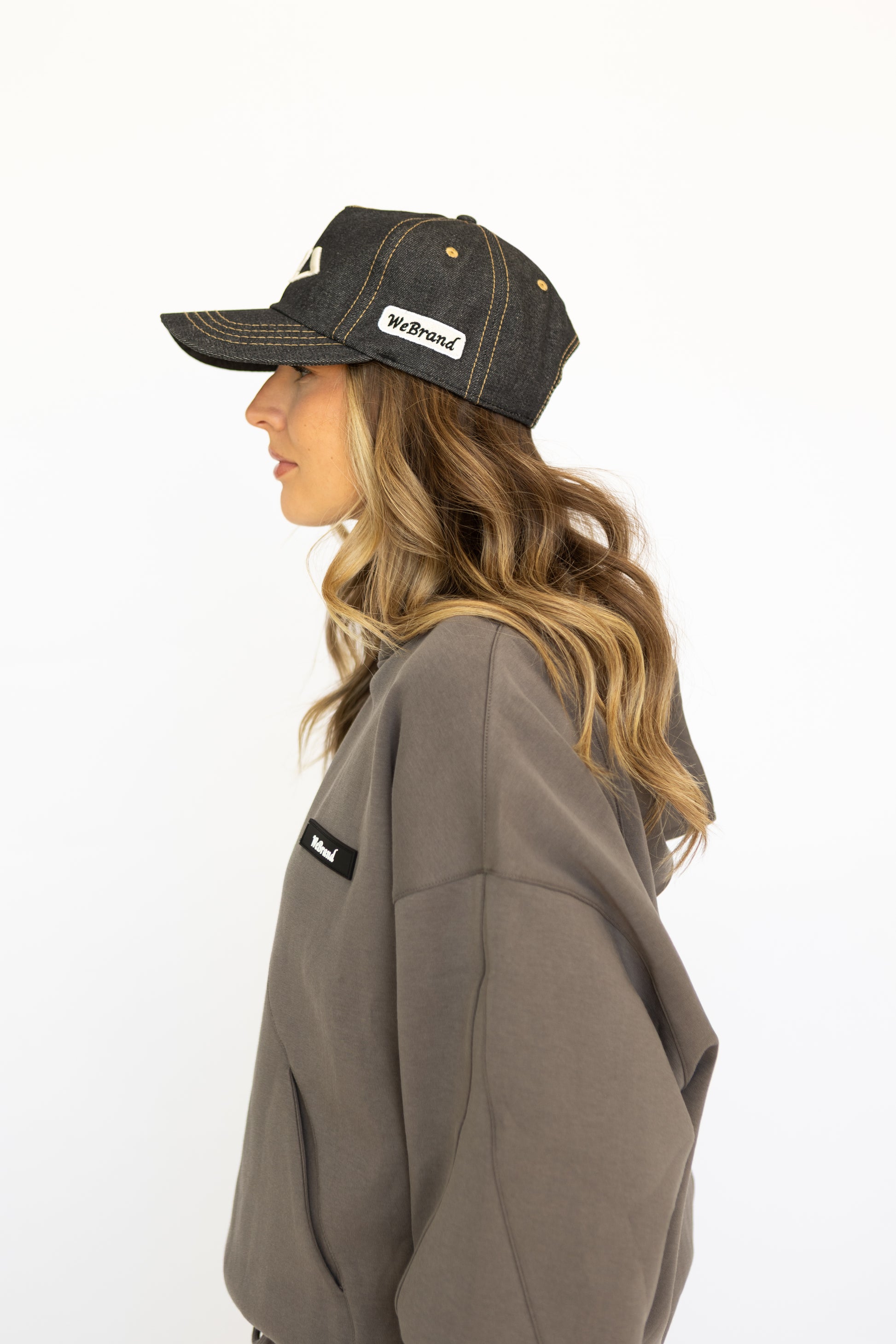 Woman wearing a cap and hoodie with visible branding on a white background