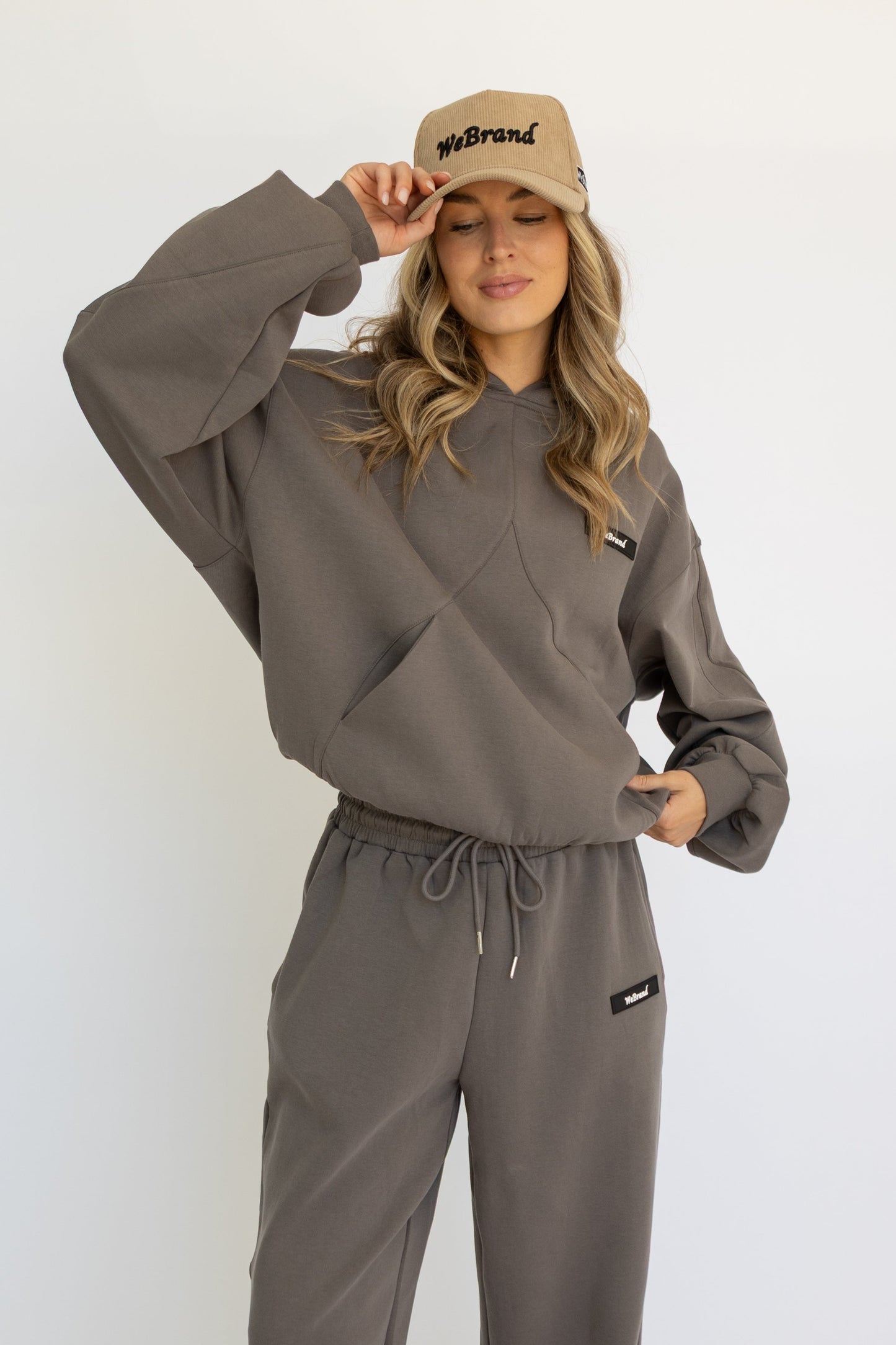 Woman wearing a gray tracksuit and beige cap on a white background