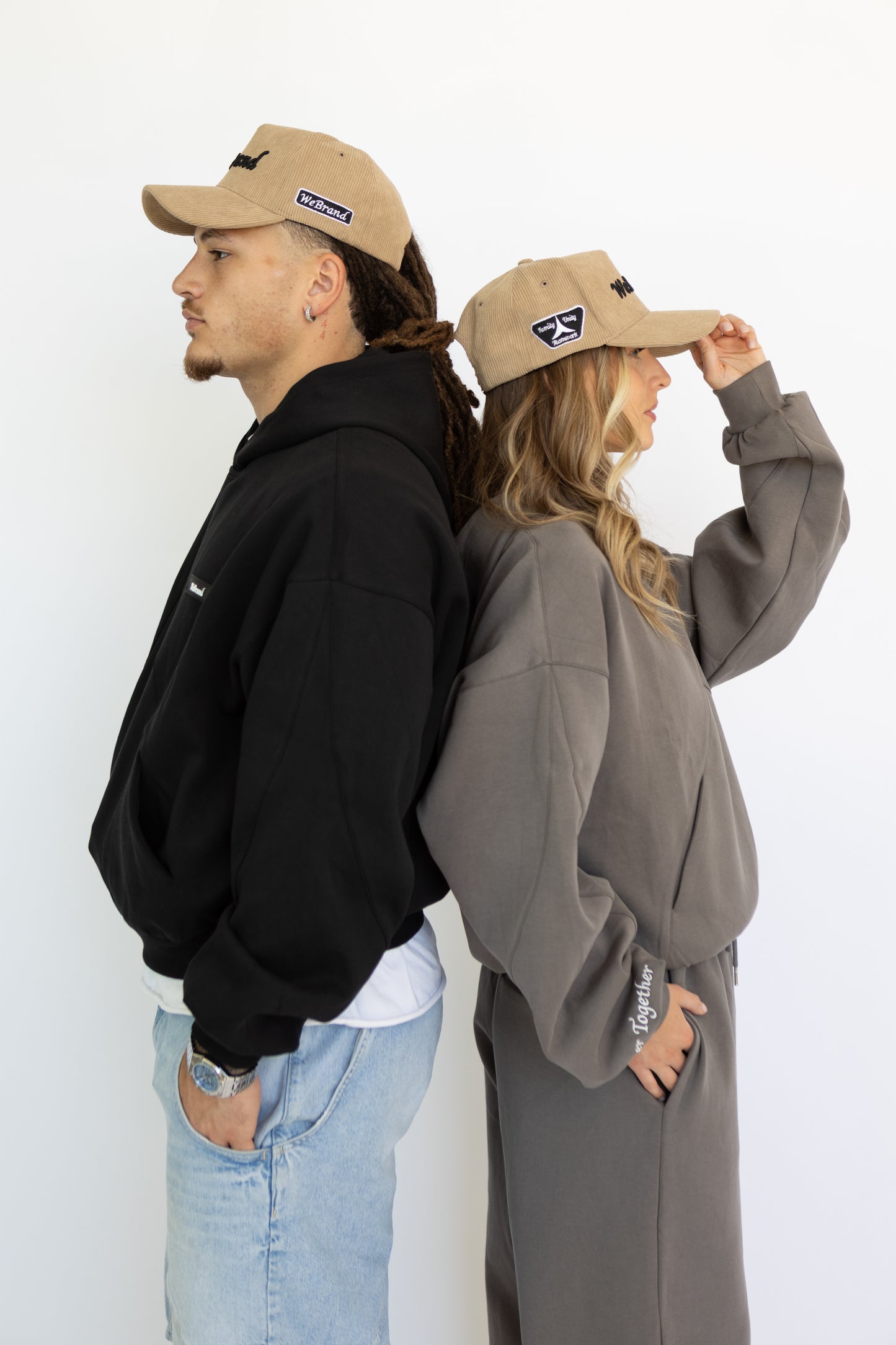 Two people wearing beige caps with a logo on a white background