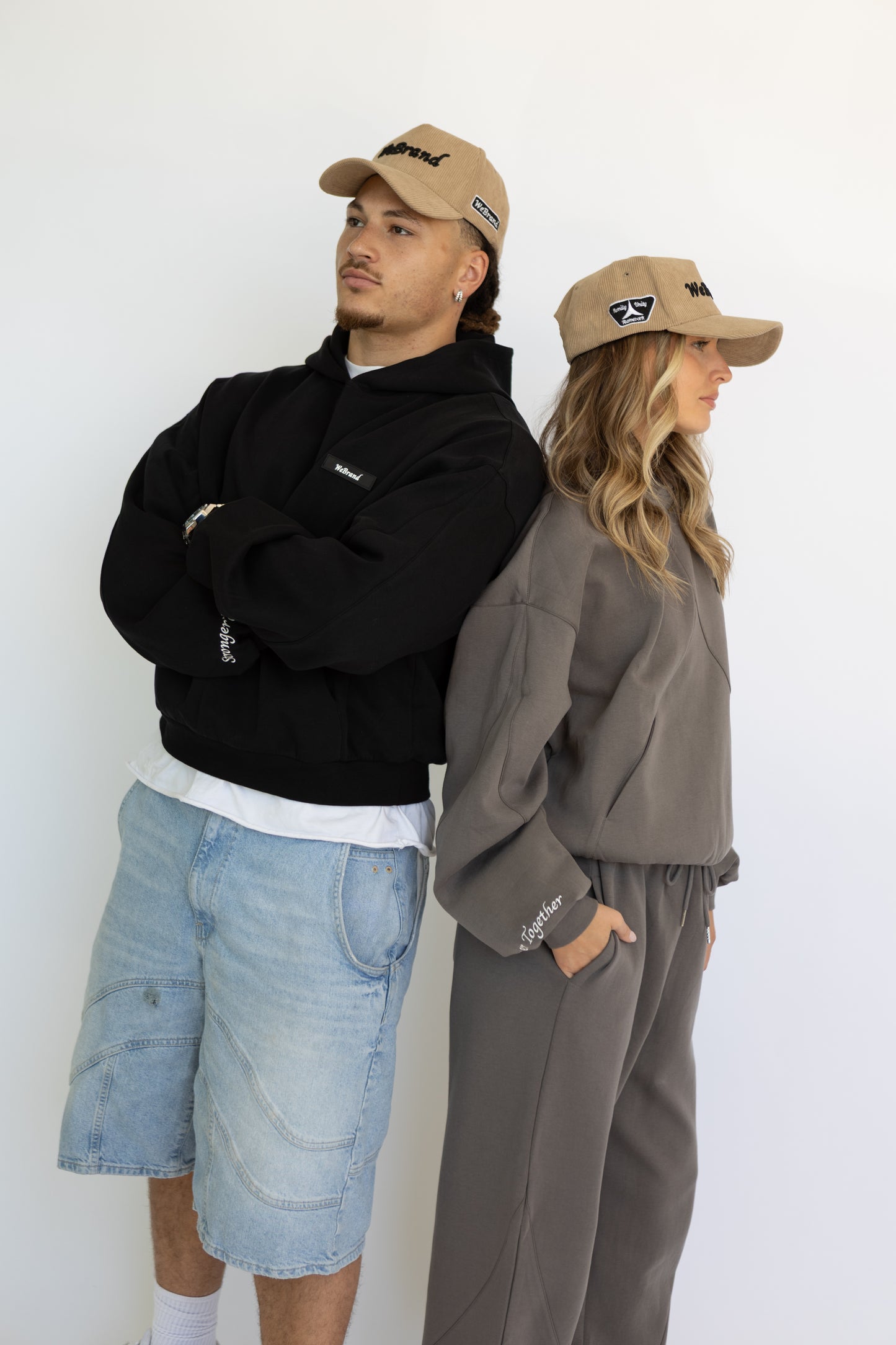Two people wearing matching caps and outfits against a white background