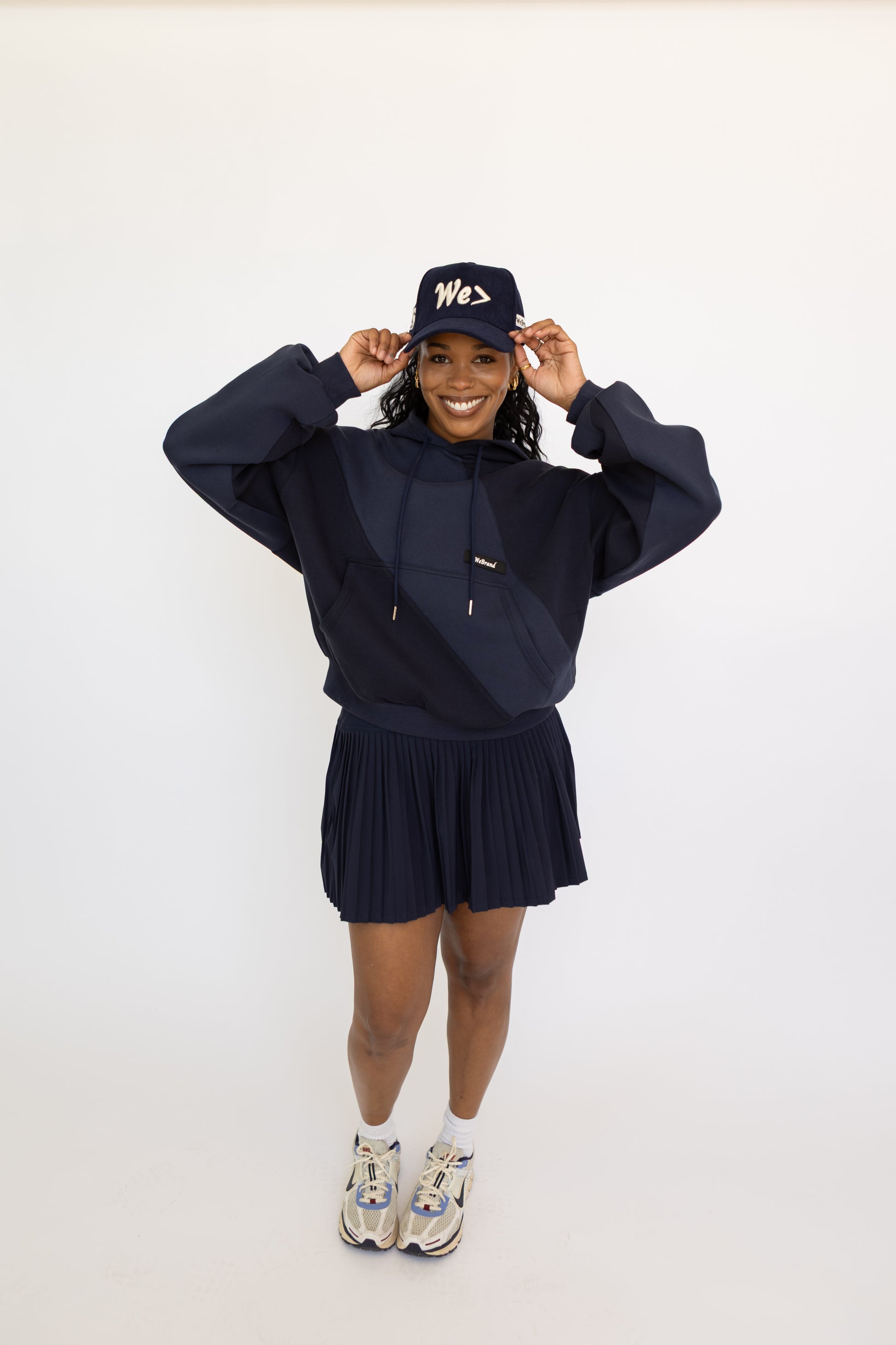Person wearing a navy blue outfit with a matching cap on a white background