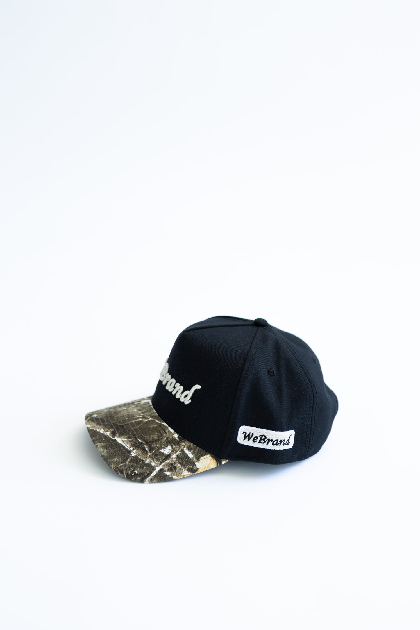 Black and camouflage baseball cap with 'WeBrand' logo on a white background