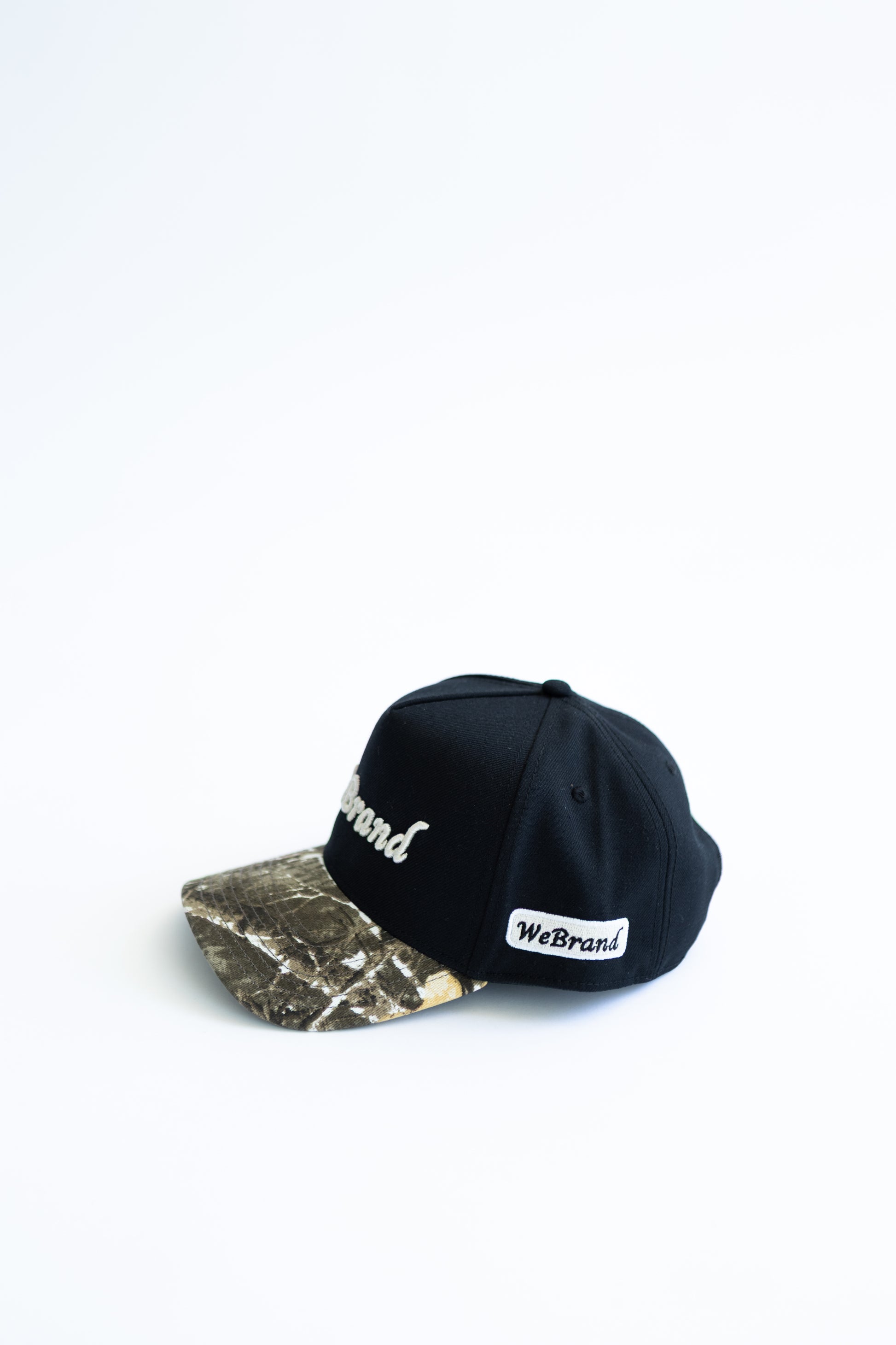 Black and camouflage baseball cap with 'WeBrand' logo on a white background