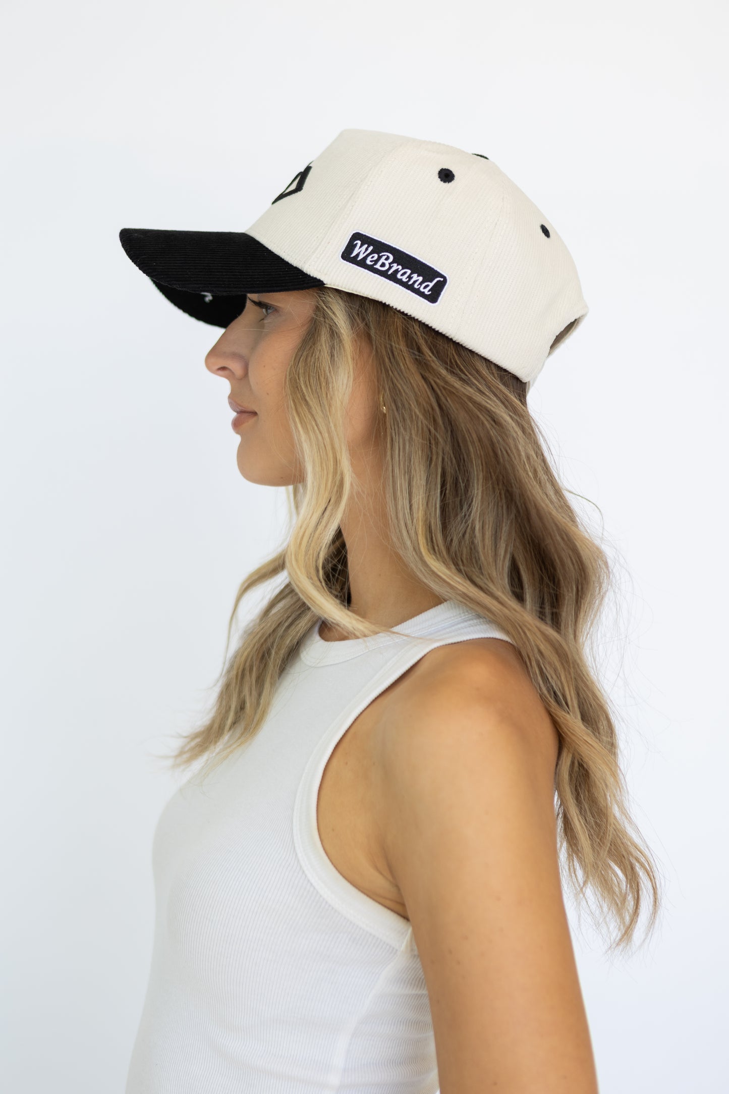 Woman wearing a black and white cap with 'WeBrand' logo on a white background