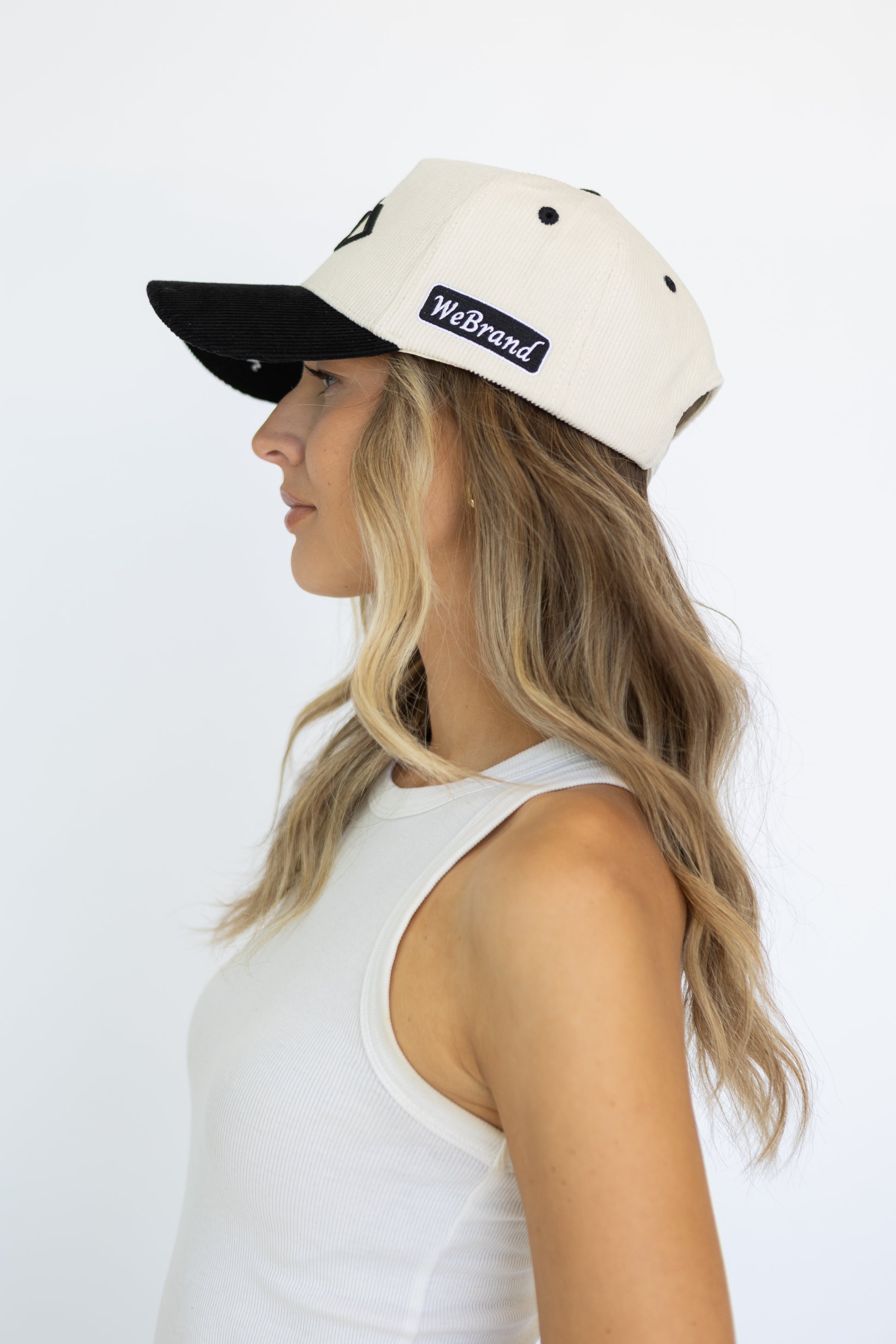 Woman wearing a black and white cap with 'WeBrand' logo on a white background
