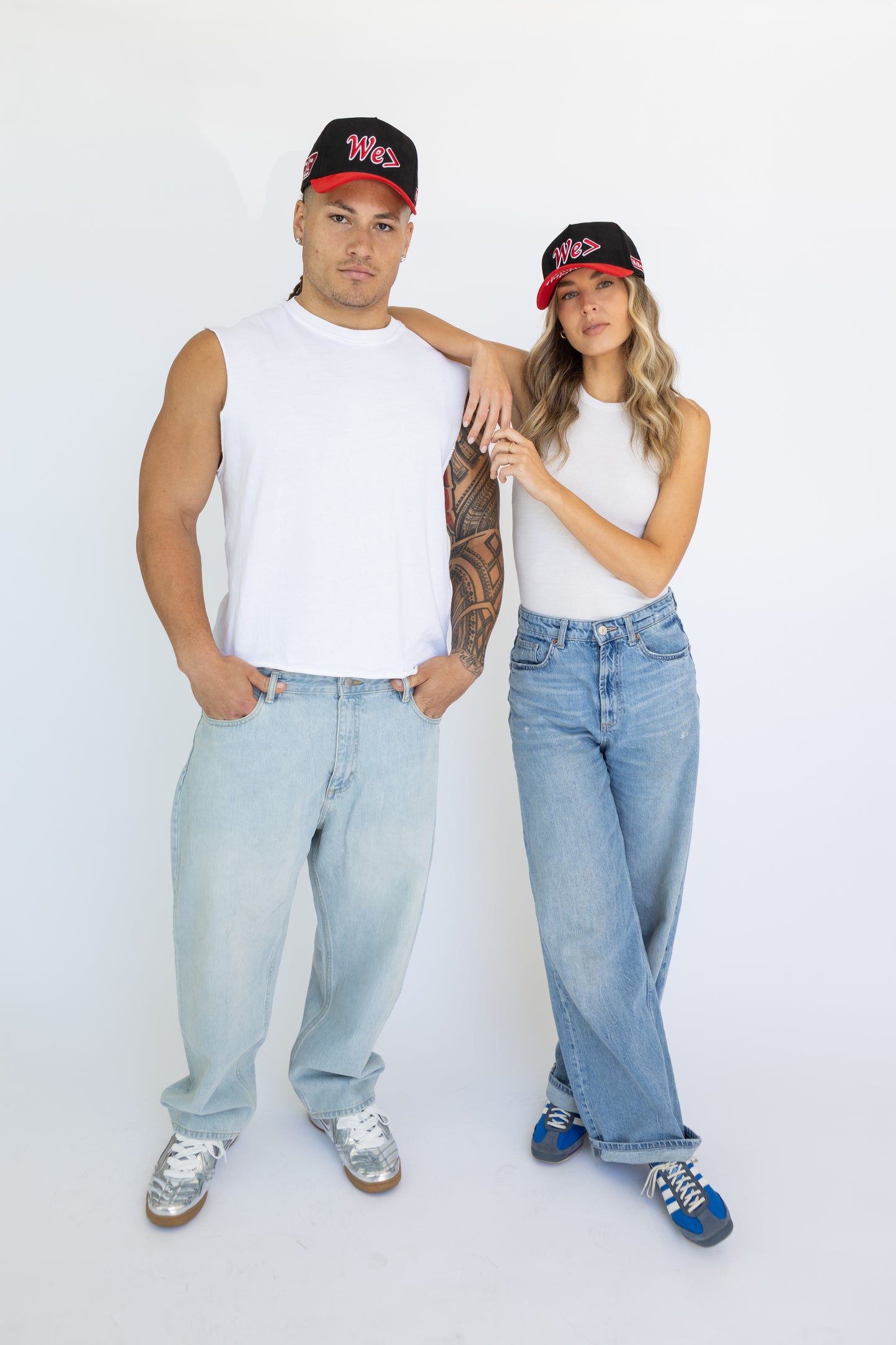 Two people wearing matching outfits with caps on a white background