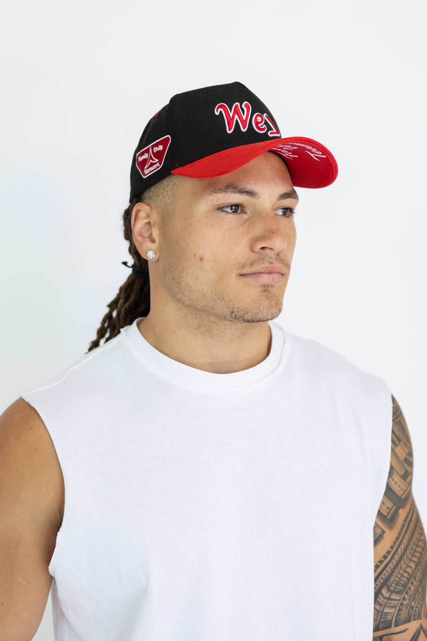 Man wearing a black and red cap with visible branding on a white background