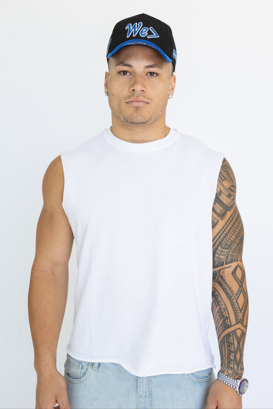Man wearing a white sleeveless shirt, black cap with blue text, and light blue jeans on a white background