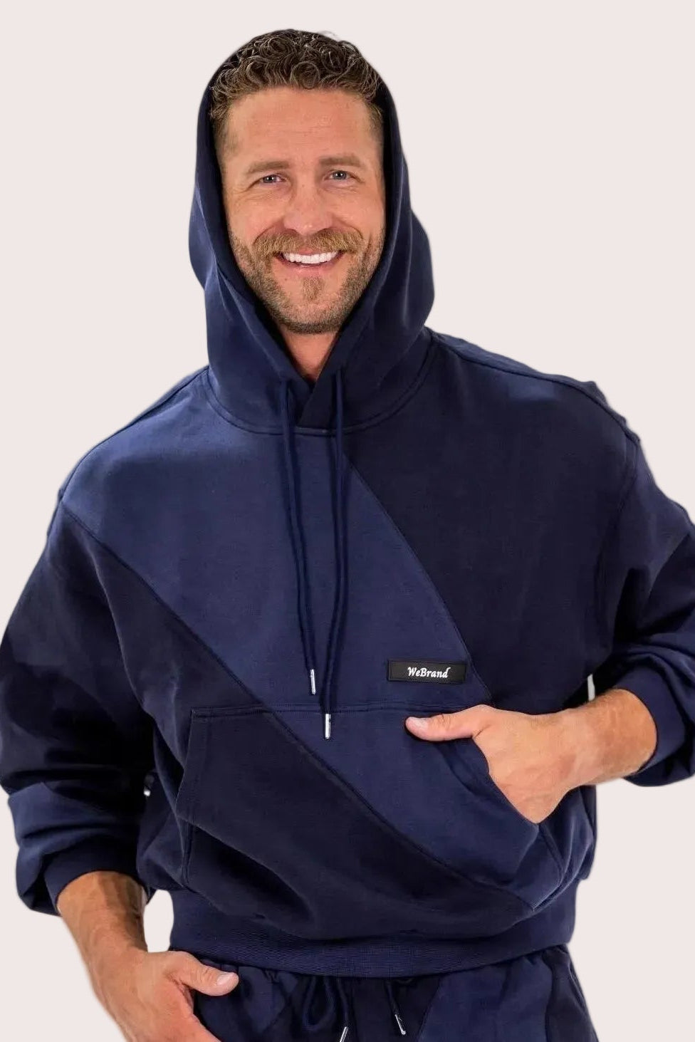 Man wearing a navy blue hoodie with a visible brand logo on a white background
