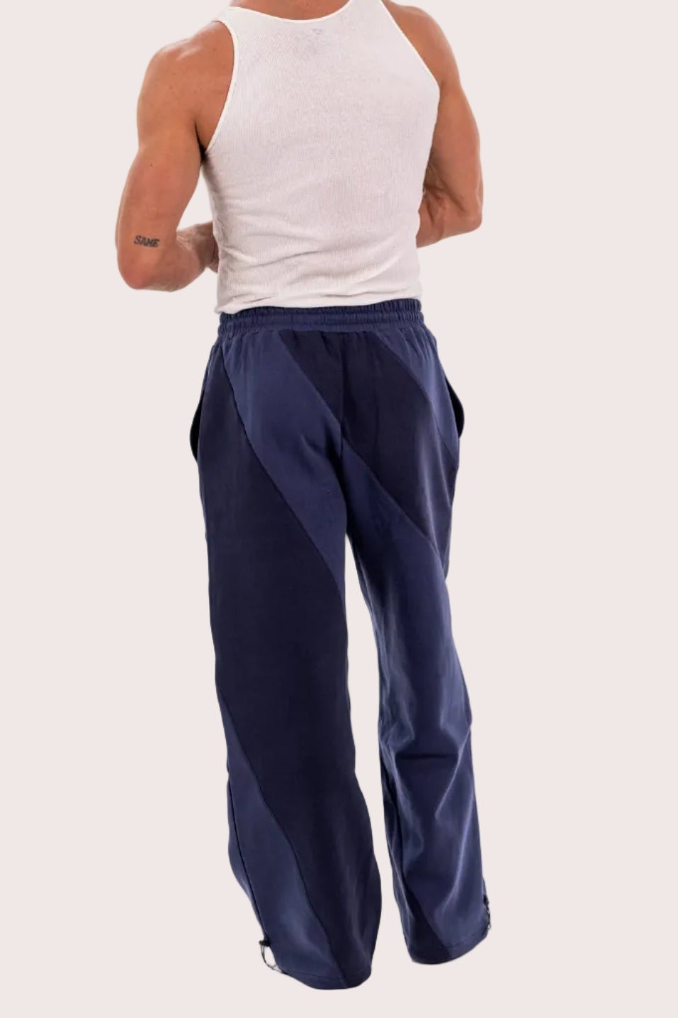 Person wearing a white tank top and navy pants on a white background
