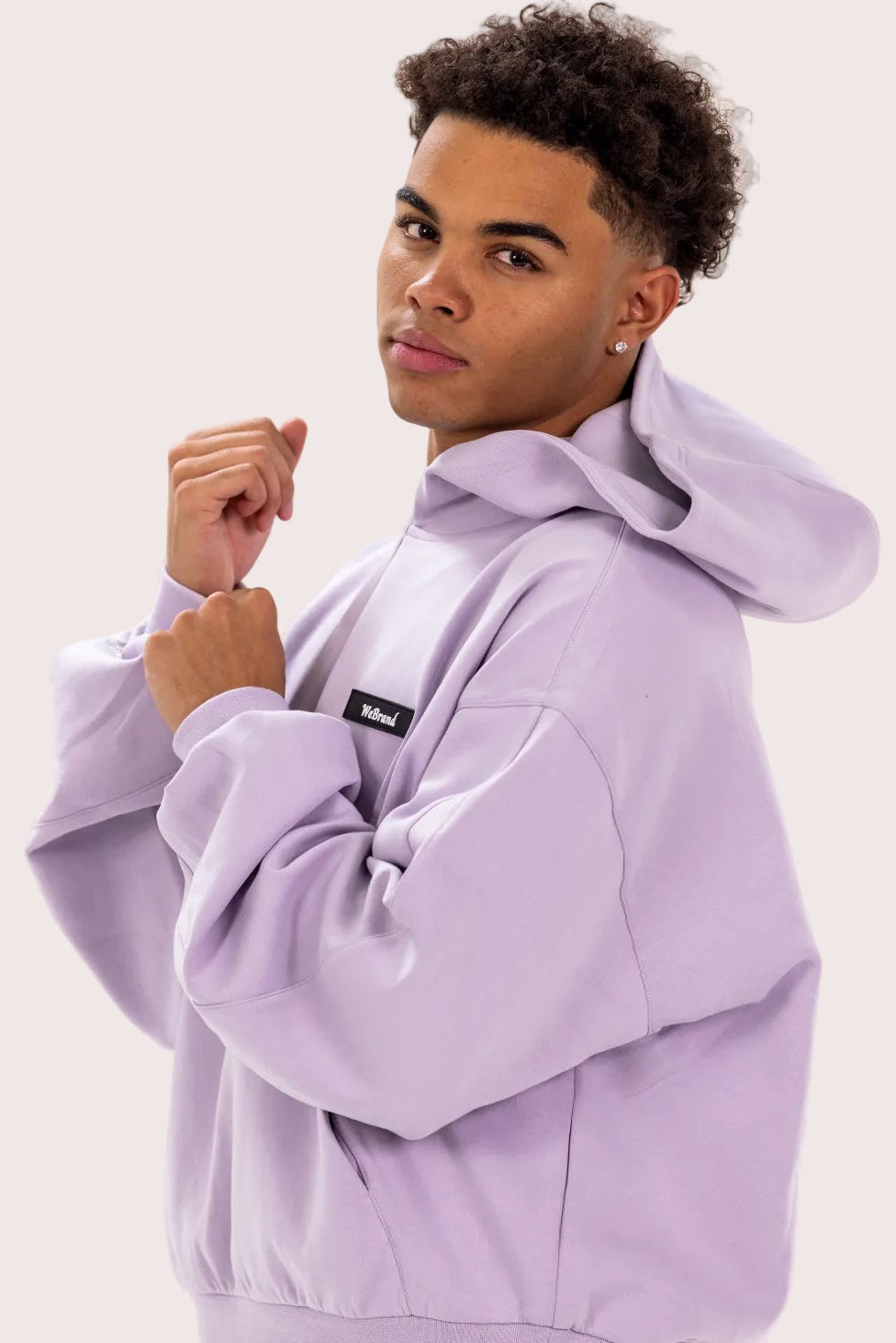 Person wearing a light purple tracksuit with visible branding on a white background