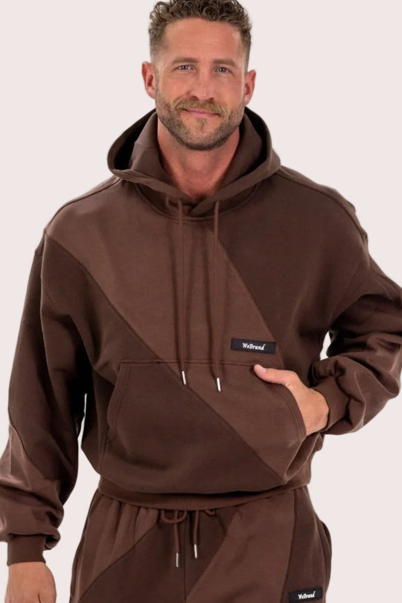 Man wearing a brown hoodie and pants with a visible brand logo on a white background
