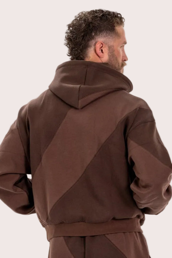 Man wearing a brown hoodie and pants on a beige background