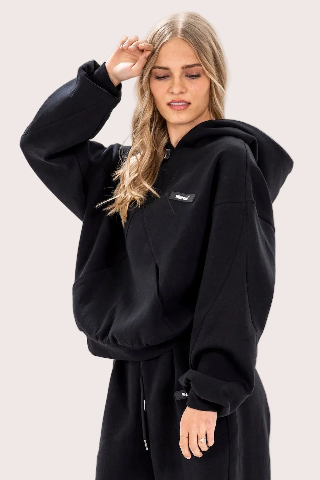 Person wearing a black hoodie and pants on a white background