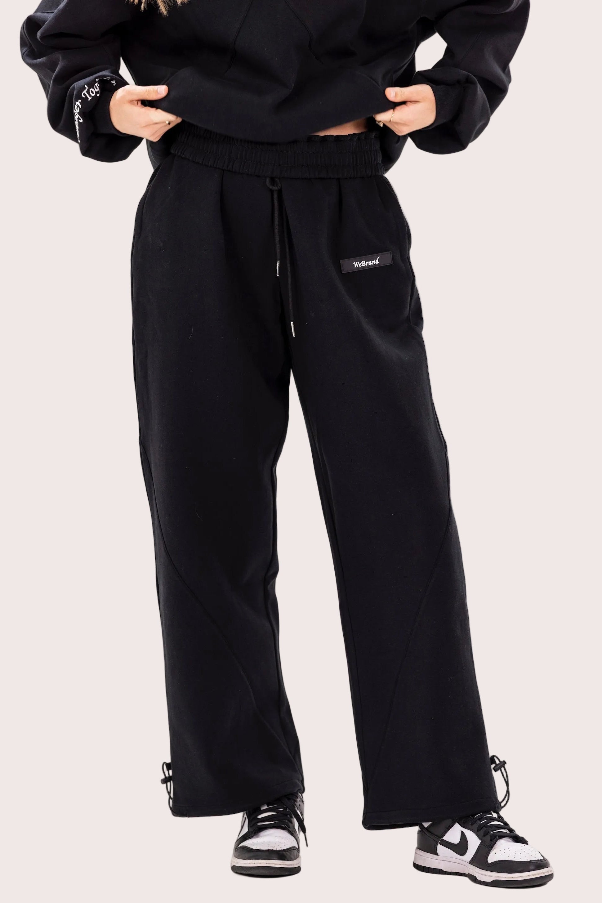 Person wearing a black tracksuit with visible branding on a white background