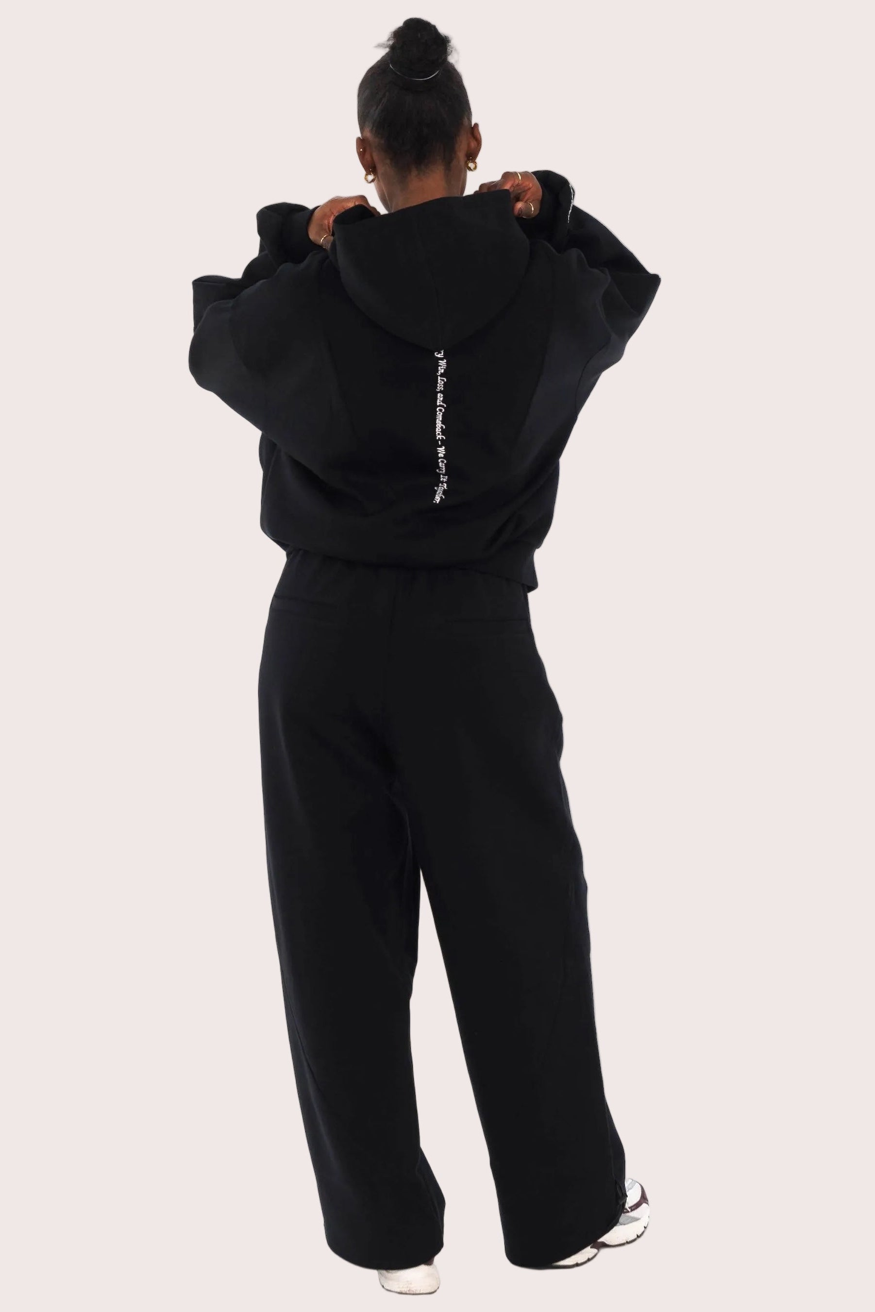 Person wearing a black tracksuit with white text on a white background