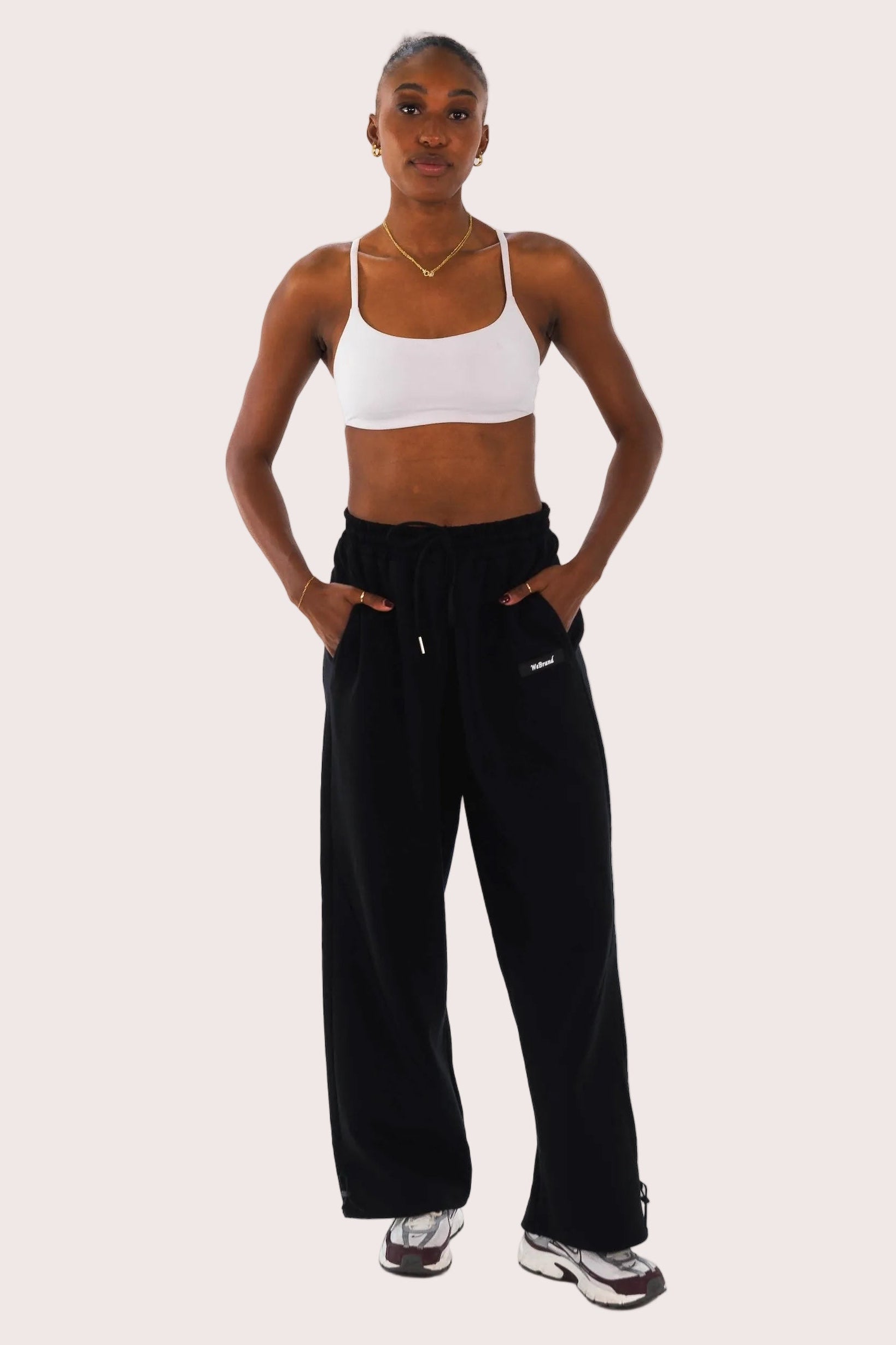 Woman wearing a white sports bra and black pants on a white background