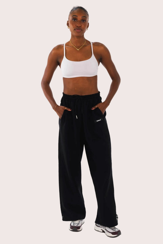 Woman wearing a white sports bra and black pants on a white background