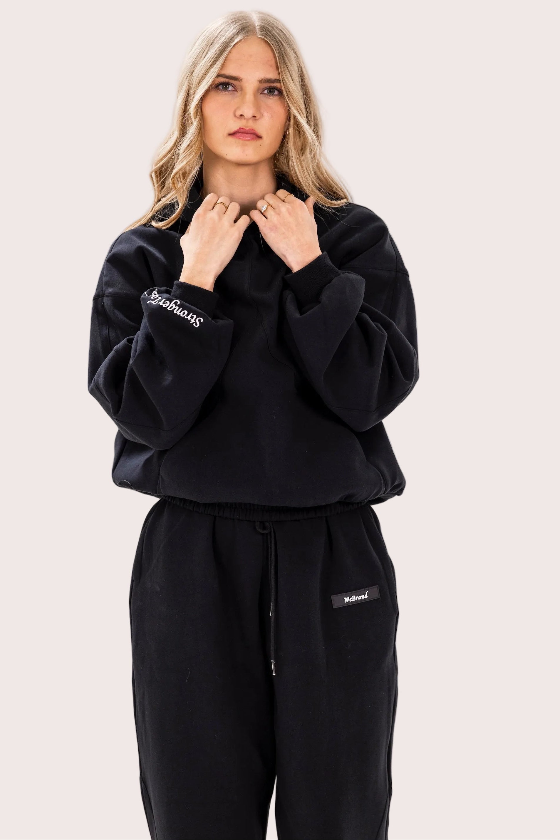 Woman wearing a black tracksuit with a logo on a white background