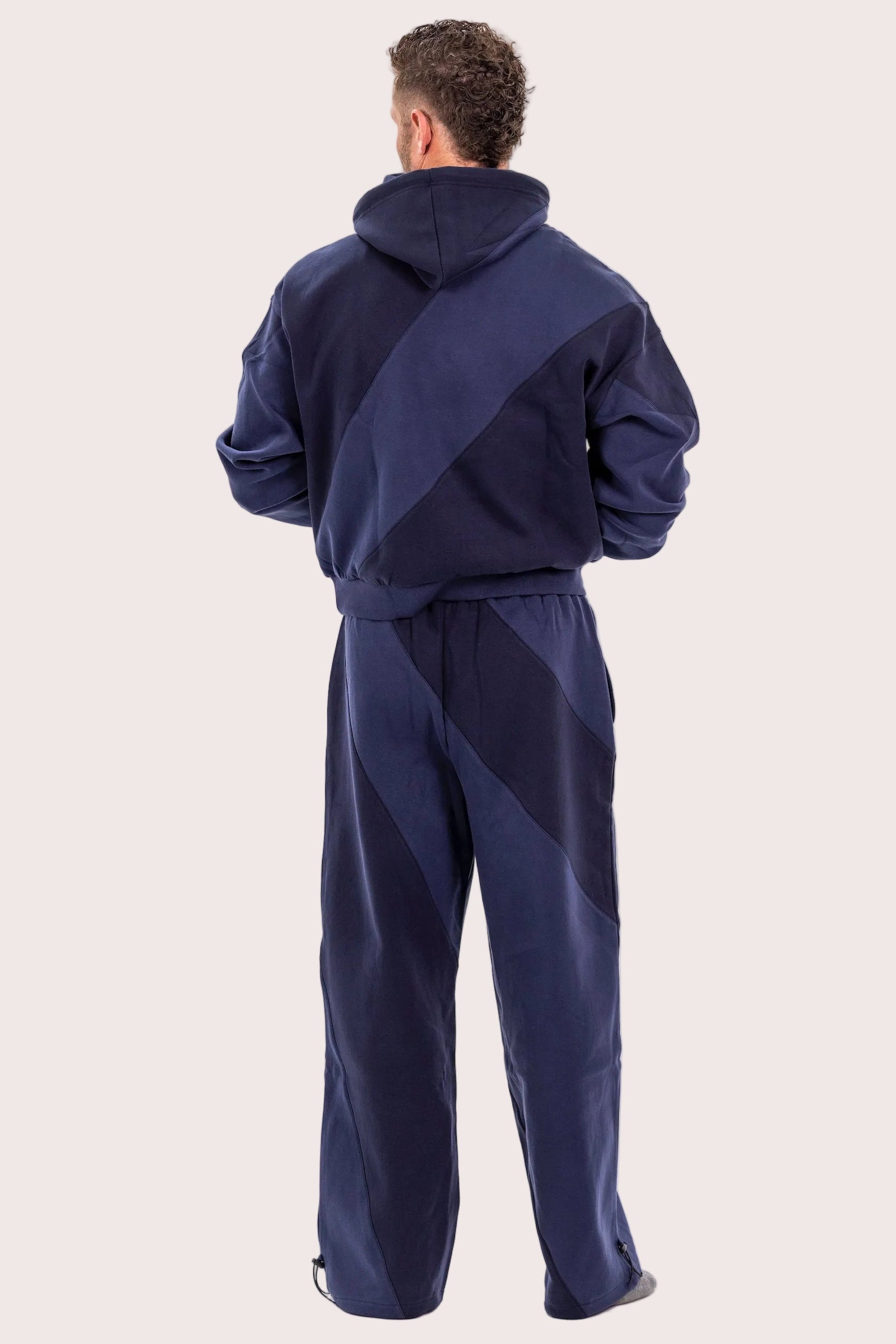 Person wearing a navy tracksuit on a light pink background