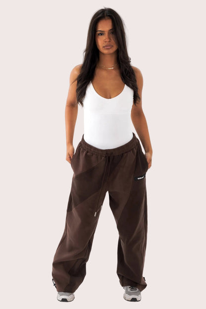 Woman wearing brown pants and a white tank top on a white background