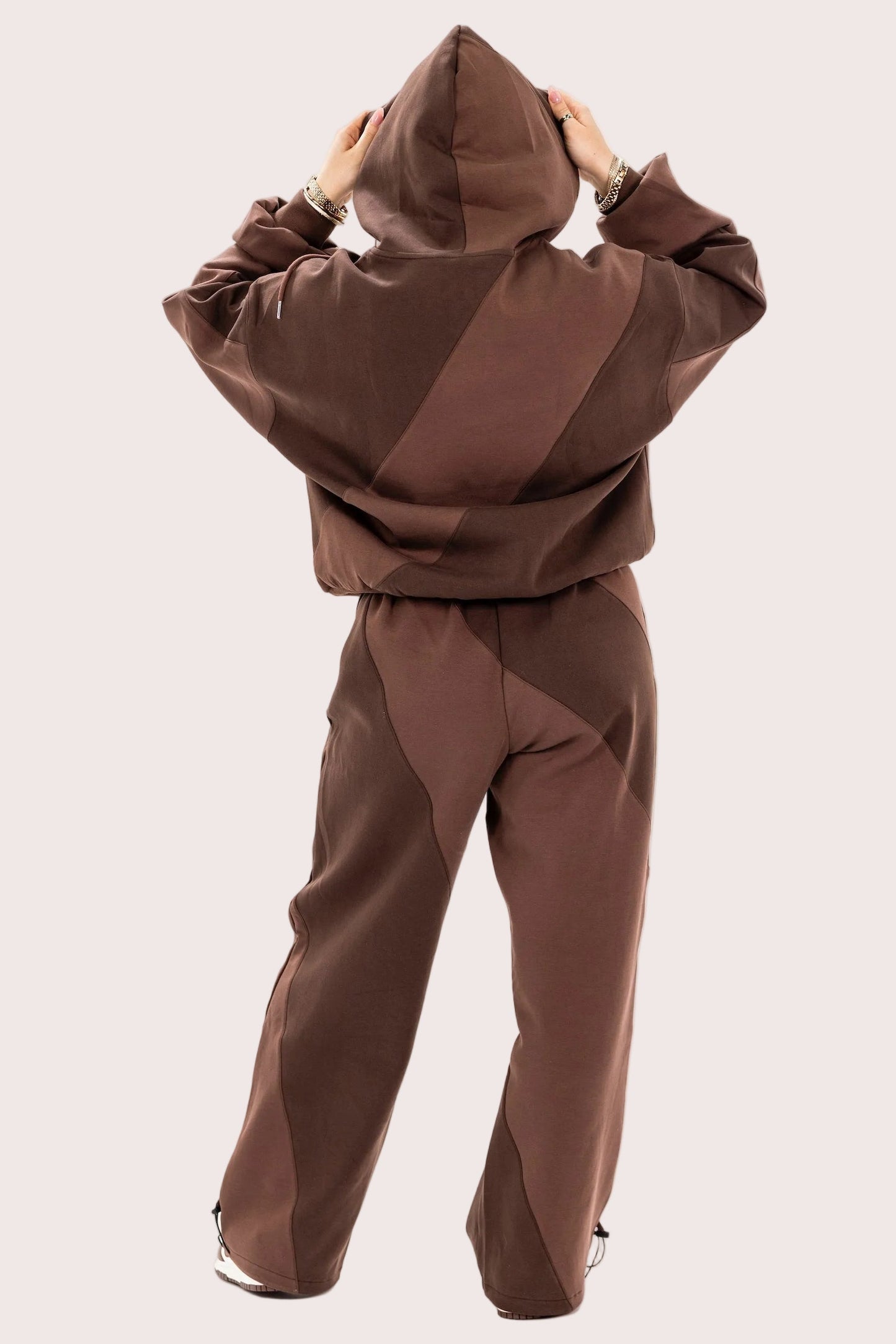 Brown tracksuit worn by a person on a light pink background