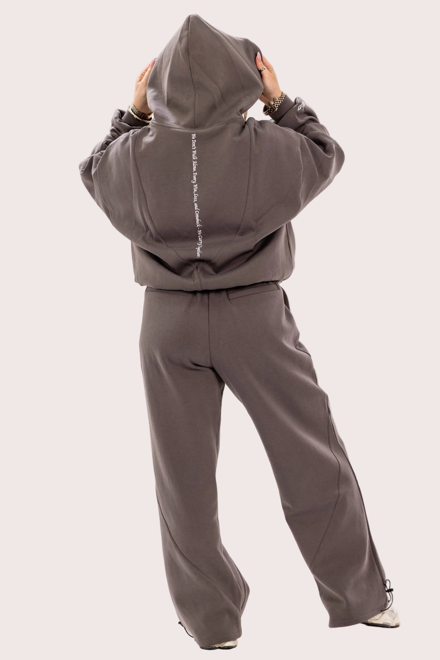Person wearing a gray hoodie and pants with a plain background