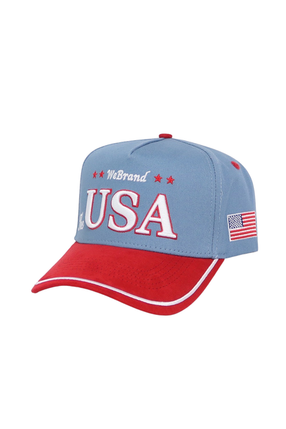 A patriotic baseball cap featuring a light blue crown with 'WeBrand USA' embroidered in red and white on the front, and a red brim with white piping and an American flag patch on the side.