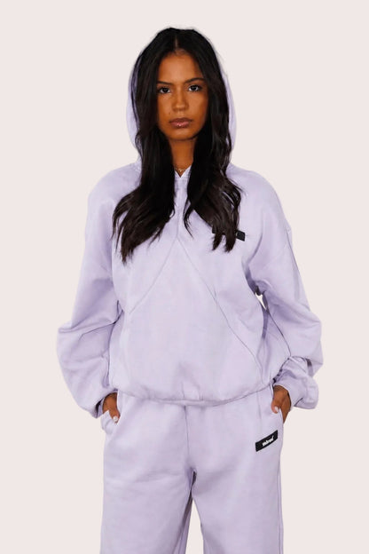 Person wearing a light purple tracksuit against a plain background