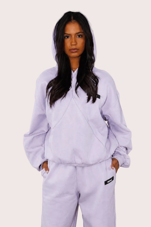 Person wearing a light purple tracksuit against a plain background